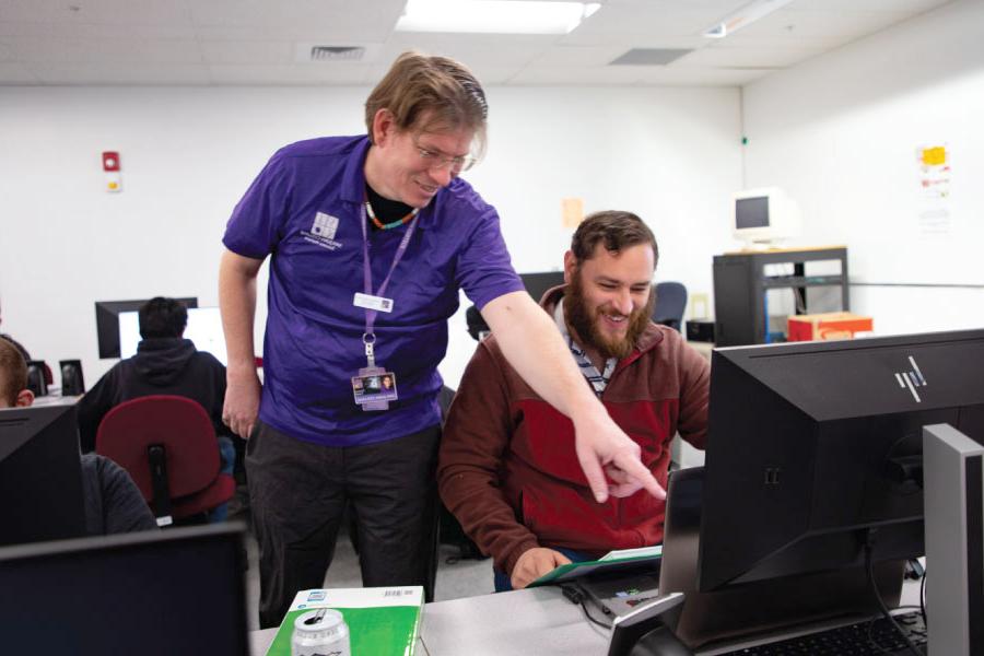 SJC Instructor pointing to computer screen, alongside student.